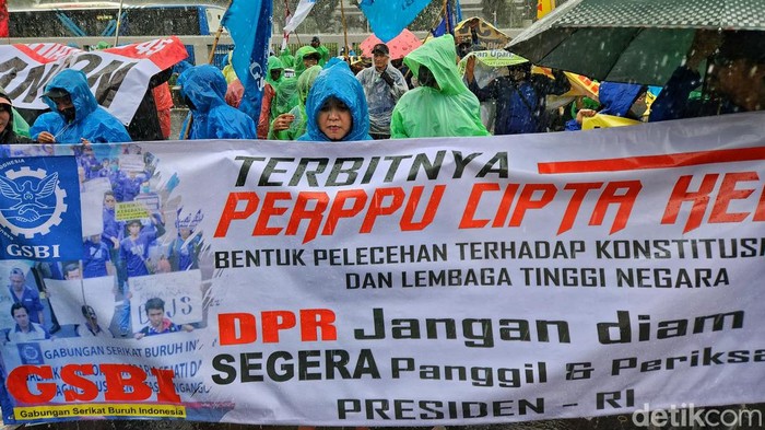 Diguyur Hujan Lebat, Massa Tetap Beraksi Tolak Perppu Ciptaker Massa pendemo dari berbagai elemen masyarakat, buruh dan LSM mulai melakukan aksi di depan gedung DPR, Jakarta, Selasa (28/2/2023). Mereka menolak Perppu Cipta Kerja. Massa bertahan di bawah guyuran hujan yang cukup lebat. Hingga pukul 14.00 WIB, aksi masih berlangsung meski hujan deras.