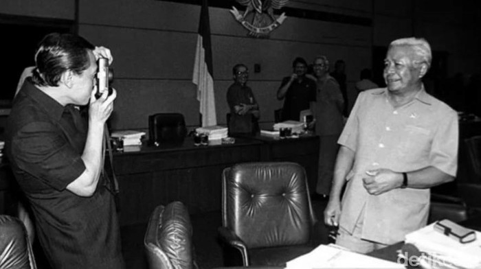 Menteri Penerangan Harmoko tengah memotret Menko Polkam Laksamana (Purn) Sudomo di sebelum sidang kabinet terbatas bidang Ekuin di Bina Graha, 4 Oktober 1989