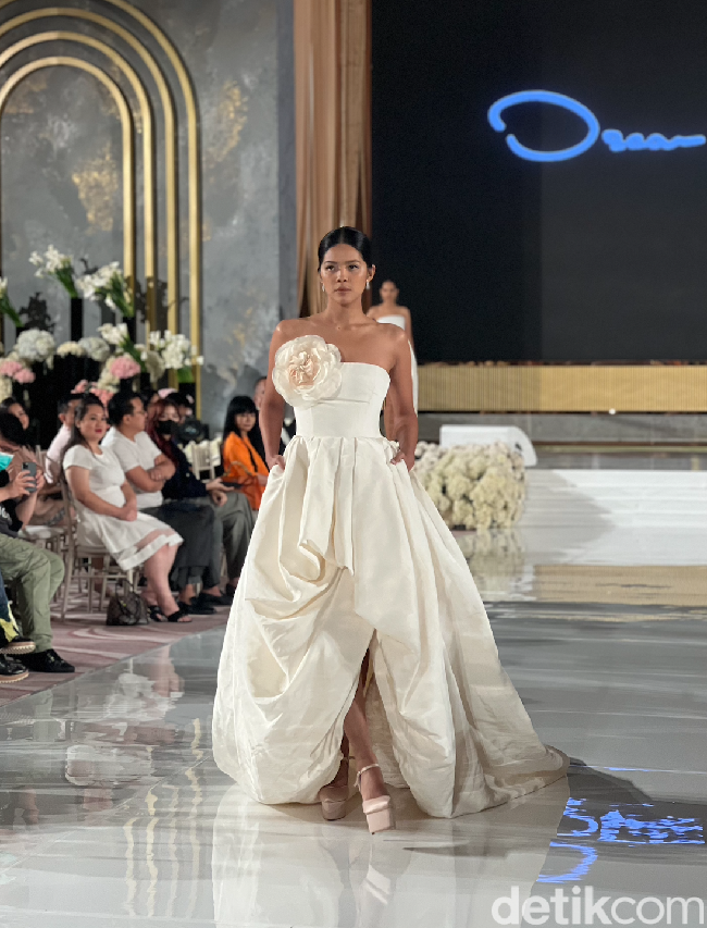 Masih dari rancangan desainer Oscar de la Renta, gaun pengantin tanpa lengan berwarna broken white yang satu ini juga tak kalah memukau. Cocok bagi kamu yang menginginkan gaun pengantin semi ball gown namun tetap terlihat simpel. Pada salah satu bagian dadanya terdapat aksen berbentuk bungan yang cukup besar dan berwarna senada dengan gaun tersebut. Foto: Wolipop/Vina Oktiani