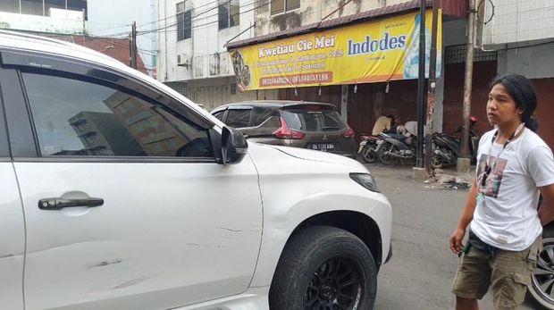Jogi saat memperlihatkan mobilnya yang rusak karena diserang oknum polisi (Foto: Istimewa)