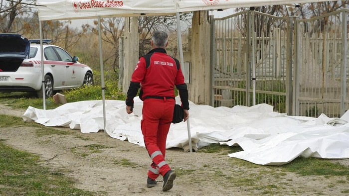 Kapal Migran Karam di Laut Italia, 62 Orang Tewas Italian Red Cross volunteers and coast guards recover a body after a migrant boat broke apart in rough seas, at a beach near Cutro, southern Italy, Sunday, Feb. 26, 2023. Rescue officials say an undetermined number of migrants have died and dozens have been rescued after their boat broke apart off southern Italy.(Antonino Durso/LaPresse via AP)
