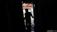 Seorang warga mengecek rumahnya yang terendam banjir setinggi lutut.