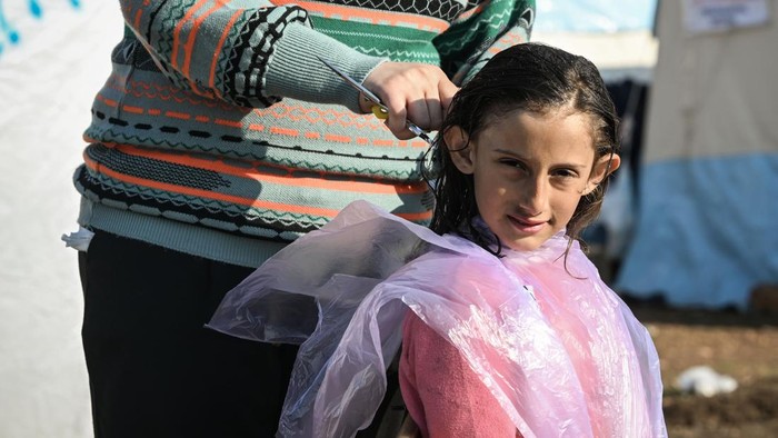 ADIYAMAN, TURKIYE - FEBRUARY 26: Volunteers, earthquake survivors from Sanliurfa, cut earthquake survivors' hair as they provide hairdresser service at the tent city set up after 7.7 and 7.6 magnitude earthquakes hit multiple provinces of Turkiye including Adiyaman, on February 26, 2023. On Feb.6 a strong 7.7 earthquake, centered in the Pazarcik district, jolted Kahramanmaras and strongly shook several provinces, including Gaziantep, Sanliurfa, Diyarbakir, Adana, Adiyaman, Malatya, Osmaniye, Hatay, and Kilis. On the same day at 1.24 p.m. (1024GMT), a 7.6 magnitude quake centered in Kahramanmaras' Elbistan district struck the region. (Photo by Esra Hacioglu Karakaya/Anadolu Agency via Getty Images)