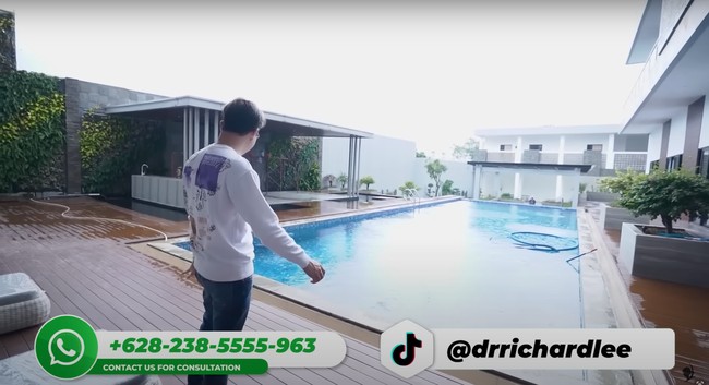 Bagian belakang rumah baru dokter Richard memiliki beragam fasilitas yang tak kalah dengan mall dan hotel. Seperti, terdapat kolam renang yang cukup luas, gazebo untuk mengadakan bakar-bakaran atau bersantai bersama kerabat, ruangan untuk gym, kolam ikan, serta lapangan untuk bermain. Foto: YouTube/dr. Richard Lee, MARS