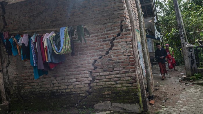 Tanah Bergerak di Lebak, 13 Rumah Warga Rusak Warga berjalan di sekitar rumahnya yang rusak akibat pergerakan tanah di Cigoong Utara, Lebak, Banten, Selasa (28/2/2023). Tingginya intensitas hujan sejak sepekan terakhir di daerah tersebut menyebabkan sebanyak 13 rumah warga retak dan satu diantaranya roboh akibat pergerakan tanah, dan hingga kini warga setempat masih bertahan di dalam rumahnya. ANTARA FOTO/Muhammad Bagus Khoirunas/rwa.
