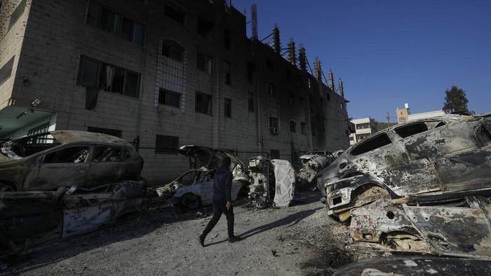 Palestinians look at damaged building and scorched cars, including some that been taken off the road for spare parts, in the town of Hawara, near the West Bank city of Nablus, Monday, Feb. 27, 2023. Scores of Israeli settlers went on a violent rampage in the northern West Bank, setting cars and homes on fire after two settlers were killed by a Palestinian gunman. Palestinian officials say one man was killed and four others were badly wounded. (AP Photo/Majdi Mohammed)