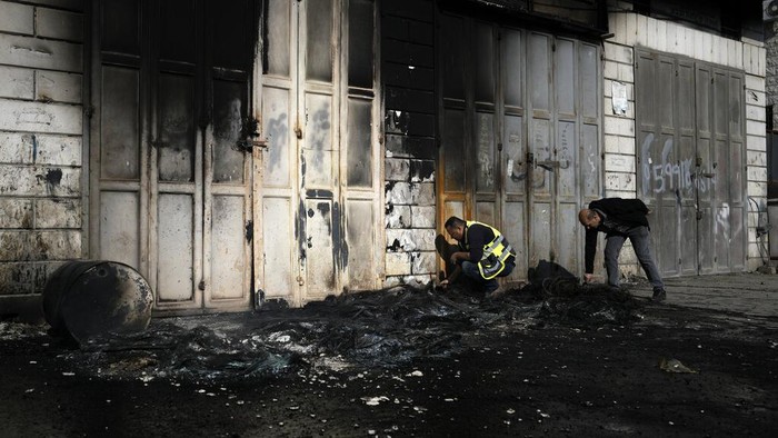 Palestinians look at damaged building and scorched cars, including some that been taken off the road for spare parts, in the town of Hawara, near the West Bank city of Nablus, Monday, Feb. 27, 2023. Scores of Israeli settlers went on a violent rampage in the northern West Bank, setting cars and homes on fire after two settlers were killed by a Palestinian gunman. Palestinian officials say one man was killed and four others were badly wounded. (AP Photo/Majdi Mohammed)