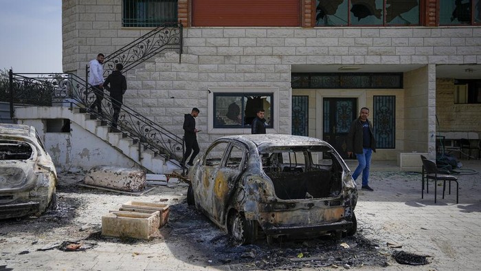 Palestinians inspect a damaged house and scorched cars in the town of Hawara, near the West Bank city of Nablus, Monday, Feb. 27, 2023. Scores of Israeli settlers went on a violent rampage in the northern West Bank, setting cars and homes on fire after two settlers were killed by a Palestinian gunman. Palestinian officials say one man was killed and four others were badly wounded. (AP Photo/Ohad Zwigenberg)