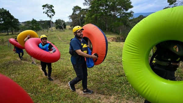 Pemandu wisata berjalan membawa ban renang di dalam sebuah peternakan dalam perjalanan mereka ke ngarai Guape, yang terletak di kotamadya La Uribe di Departemen Meta, Kolombia, Minggu (19/2/2023). Pemandu wisata berjalan membawa ban renang di dalam sebuah peternakan dalam perjalanan mereka ke ngarai Guape, yang terletak di kotamadya La Uribe di Departemen Meta, Kolombia, Minggu (19/2/2023).