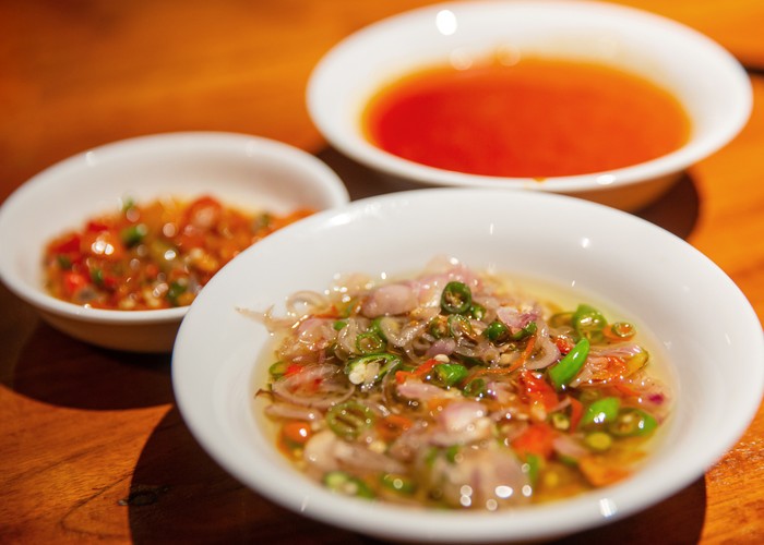 Close up shot of delicious spicy Balinese raw chili chopped with shallot and lemongrass ( sambal matah bali ). Theres various chili condiment on the side.