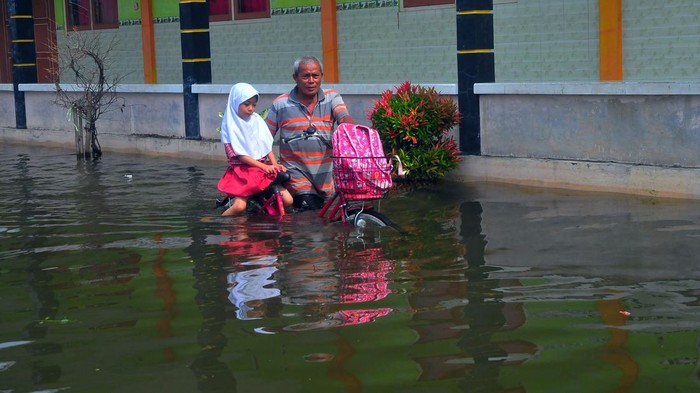 Siswa pulang membonceng sepeda dengan kakeknya usai mengikuti Ujian Tengah Semester (UTS) di SD N 4 Karangrowo yang tergenang banjir di Desa Karangrowo, Undaan, Kudus, Jawa Tengah, Rabu (1/3/2023). Sebanyak 158 siswa terpaksa melaksanakan UTS di Mushola dan sebagian lainnya di Sekolah dengan halaman yang tergenang akibat banjir yang melanda wilayah itu sejak sepekan terakhir. ANTARA FOTO/Yusuf Nugroho/aww.