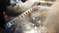 Asap mengepul dari kereta yang terguling setelah tabrakan di dekat kota Larissa, Yunani, Rabu (1/3/2023) dini hari waktu setempat. Sedikitnya 26 orang tewas dan 85 orang lainnya mengalami luka-luka dalam kecelakaan tersebut.  