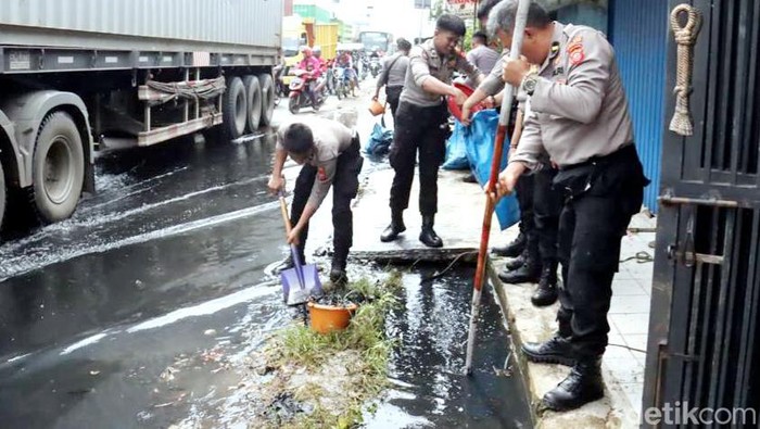 Personel Polres Karawang sedang membersihkan drainase di Jalan Pantura Karawang