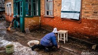 Nenek itu memperbaiki jendela kacanya yang pecah usai diserang Rusia. Dimitar Dilkoff/AFP via Getty Images.
