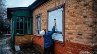 Nenek itu menutup jendela yang bolong dengan kain spanduk berwarna putih. Dimitar Dilkoff/AFP via Getty Images.