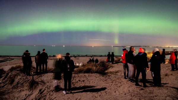 Orang-orang mengamati Aurora borealis atau Cahaya Utara dari Pantai Hornbaek, Sealand, Denmark, Senin (27/2/2023).  