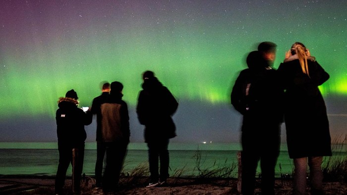 People observe the Northern Lights from Hornbaek beach, Sealand, Denmark February 27, 2023. Ritzau Scanpix/Mads Claus Rasmussen via REUTERS    ATTENTION EDITORS - THIS IMAGE WAS PROVIDED BY A THIRD PARTY. DENMARK OUT. NO COMMERCIAL OR EDITORIAL SALES IN DENMARK.