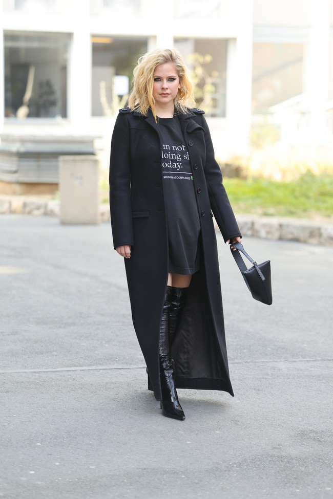 Kaus panjang tersebut dipakai selaikanya sebuah little black dress. Baju tersebut ditemani coat panjang yang menyentuh lantai dan boots kulit yang tingginya hingga ke atas pangkal paha. (Foto: Jacopo Raule/Getty Images)
