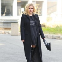 Kaus panjang tersebut dipakai selaikanya sebuah little black dress. Baju tersebut ditemani coat panjang yang menyentuh lantai dan boots kulit yang tingginya hingga ke atas pangkal paha. (Foto: Jacopo Raule/Getty Images)