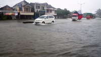 Sejumlah kendaraan menerobos jalan yang tergenang banjir di jalur Pantura, Desa Jati Wetan, Kudus, Jawa Tengah, Kamis (2/3/2023).