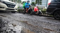 Jalan yang berlubang membuat para pengendara melambatkan kecepatannya.
