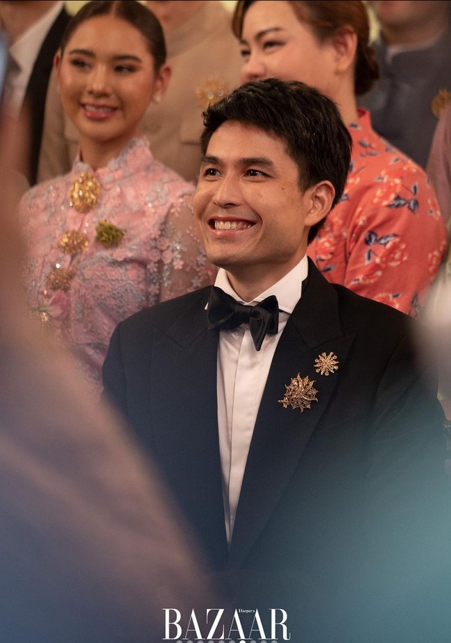 Sang mempelai pria, Oak Phakwa, tampil elegan berbalut setelan jas hitam. Dua bros berwarna keemasan menghiasi dada kirinyaa. Foto: Instagram/@bazaarthailand