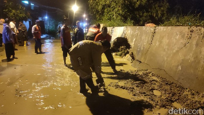 Petugas gabungan gotong royong membersihkan jalan dari lumpur sisa banjir di Mangkang Kulon, Semarang, Kamis (2/3/2023).