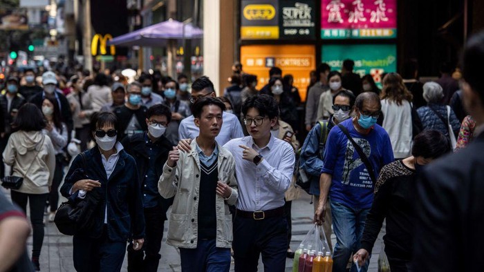 Two men (C) chat as they walk through the central business district in Hong Kong on March 1, 2023, as the government lifted a mask mandate on March 1. (Photo by ISAAC LAWRENCE / AFP) (Photo by ISAAC LAWRENCE/AFP via Getty Images)