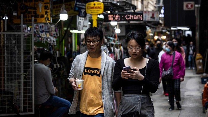 Potret Aktivitas Warga Hong Kong yang Kini Bebas Masker People (C) walk through the central business district in Hong Kong on March 1, 2023, as the government lifted a mask mandate on March 1. (Photo by ISAAC LAWRENCE / AFP) (Photo by ISAAC LAWRENCE/AFP via Getty Images)