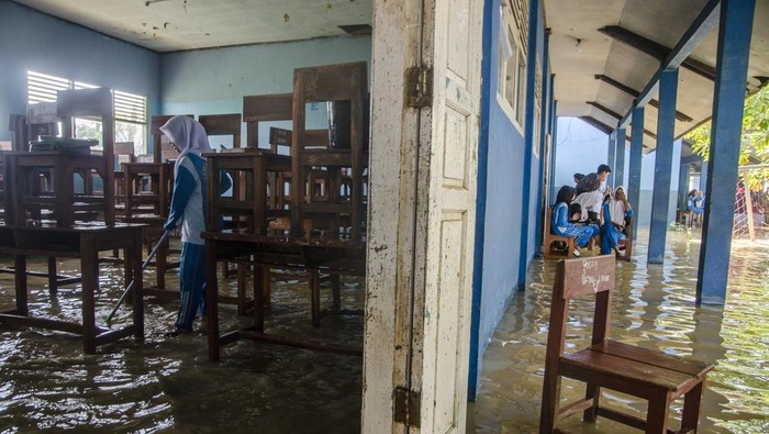Siswa membersihkan kursi kelas pada genangan banjir di SMPN 1 Telukjambe Barat, Karangligar, Kabupaten Karawang, Jawa Barat, Jumat (3/3/2023). Sekolah tersebut menjadi salah satu fasilitas pendidikan yang terendam setinggi 30 centimeter hingga 1,5 meter akibat banjir yang melanda sejak senin (27/2) sehingga mengganggu jalannya aktivitas pedidikan. ANTARA FOTO/Novrian Arbi/nym.