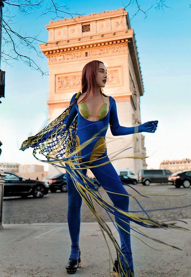 Unggahan tersebut memperlihatkan wanita yang lebih akrab dikenal sebagai Ms. Kuan itu berpose di depan Arc de Triomphe, salah satu monumen ikonis di Paris. Ia berbalut sebuah bodysuit biru yang dihiasi rumbai panjang menjuntai dengan aksen kuning. (Foto: Instagram/@ms_kuan)