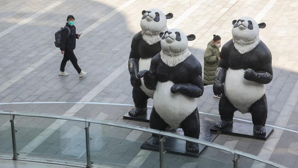 Pengunjung berjalan melewati tiga patung panda di Sinar Mas Plaza di Shanghai, China, Kamis (2/3/2023).