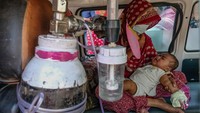Seorang wanita duduk di dalam ambulans bersama anaknya, yang menderita masalah pernapasan, di sebuah rumah sakit di Kolkata, India, Kamis (2/3/2023). (Dipayan Bose/Getty Images)  