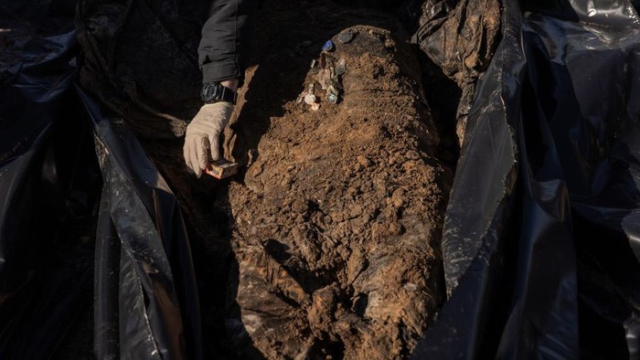 Polisi Gali Kuburan Jenazah Korban Warga Sipil Serangan Rusia di Kyiv BORODYANKA, UKRAINE - MARCH 02: (EDITOR'S NOTE: Image contains graphic content) A man stands next to a mass grave from where exhumed remains of three civilians killed at the time of the Russian occupation, at a cemetery, on March 2, 2023 in Borodyanka, near Kyiv, Ukraine. Ukrainian authorities said the bodies are those of civilian victims of Russia's offensive in the area last year. Kyiv's northwestern suburbs saw intense fighting early in Russia's 2022 invasion, as Moscow tried to seize the Ukrainian capital. Russian forces ultimately withdrew from the area. (Photo by Roman Pilipey/Getty Images)