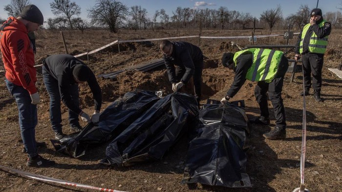 BORODYANKA, UKRAINE - MARCH 02: (EDITOR'S NOTE: Image contains graphic content)  A man stands next to a mass grave from where exhumed remains of three civilians killed at the time of the Russian occupation, at a cemetery, on March 2, 2023 in Borodyanka, near Kyiv, Ukraine. Ukrainian authorities said the bodies are those of civilian victims of Russia's offensive in the area last year. Kyiv's northwestern suburbs saw intense fighting early in Russia's 2022 invasion, as Moscow tried to seize the Ukrainian capital. Russian forces ultimately withdrew from the area. (Photo by Roman Pilipey/Getty Images)