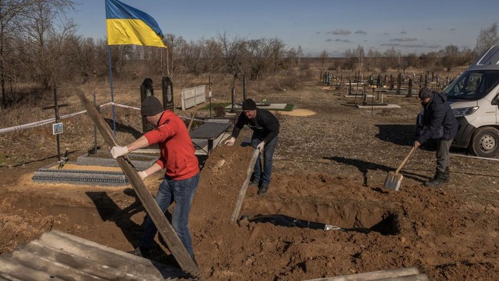 BORODYANKA, UKRAINE - MARCH 02: (EDITOR'S NOTE: Image contains graphic content)  A man stands next to a mass grave from where exhumed remains of three civilians killed at the time of the Russian occupation, at a cemetery, on March 2, 2023 in Borodyanka, near Kyiv, Ukraine. Ukrainian authorities said the bodies are those of civilian victims of Russia's offensive in the area last year. Kyiv's northwestern suburbs saw intense fighting early in Russia's 2022 invasion, as Moscow tried to seize the Ukrainian capital. Russian forces ultimately withdrew from the area. (Photo by Roman Pilipey/Getty Images)