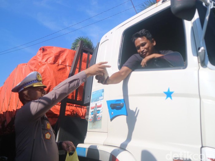 Polisi membagikan bungkusan nasi dan kopi ke sopir truk yang terjebak macet di jalur Pantura Pati, Jumat (3/3/2023) pagi.