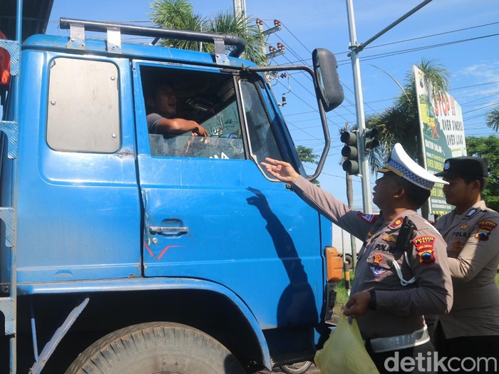Polisi membangunkan sopir truk yang tertidur karena terjebak macet berjam-jam di jalur Pantura Pati-Rembang, Jumat (3/3/2023) pagi.