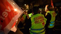 Mereka membawa bendera sembari berdiri di depan trem jalanan.