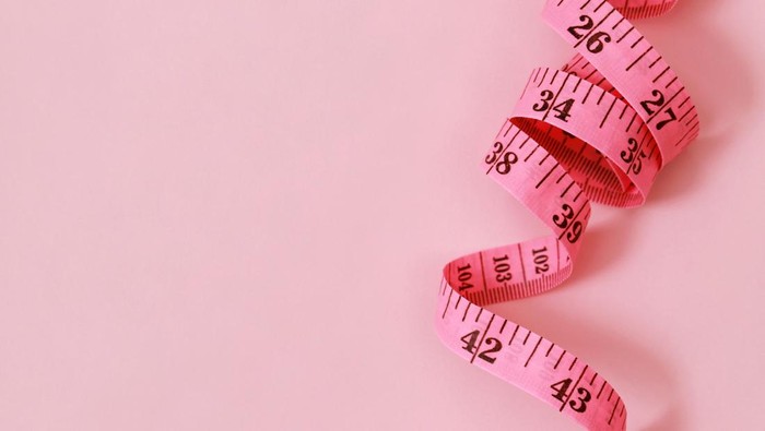 tape measure for obese people on a pink background soft focus