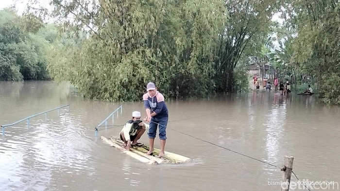 WArga di Bojonegoro yang kebanjiran membuat perahu rakit dari pohon pisang untuk menyeberang