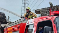 Petugas Damkar menyemprotkan air ke puing-puing rumah warga.