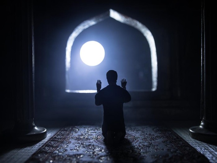 A realistic Arabian interior miniature with window and columns. Silhouette of muslim praying on carpet near window. Festive greeting card, invitation for Muslim holy month Ramadan Kareem. Selective focus