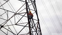 Seorang petugas PLN tampak memanjat menara SUTET untuk melakukan perbaikan.