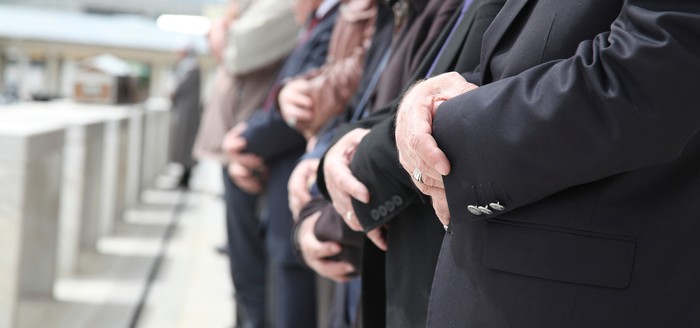 Close Up Shot of Muslim People Tied Hands. One Persons Hand on Foreground is in Focus and the Others on Background is Out of Focus. Coffins also in front of the People. Islamic Ceremony for Dead People. Whorshippers Standing next to the Coffins and Pray.