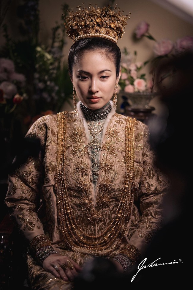 Baju pengantin Nong Poy yang berupa jubah ini dibuat dari sutra Prancis yang dipotong dengan kerah tinggi dan lengan lipit. Gaun ini juga berhiaskan bulu kelinci yang disulam motif poppy emas. Menurut adat peranakan, ini merupakan simbol dari ingatan, harapan dan kedamaian untuk masa depan. Foto: Dok. Instagram @chartmakeup, @achirakul