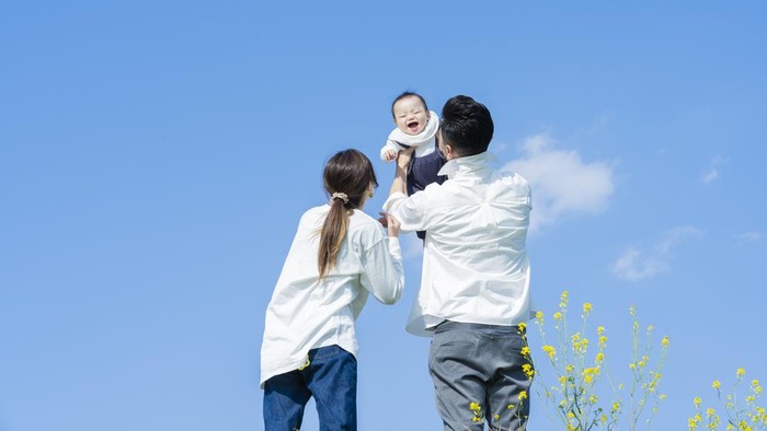 1309939432 Parents holding their baby high under the blue sky