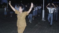 Seorang ibu guru sekolah menengah atas (SMA) memandu gerakan senam sebelum masuk kelas.