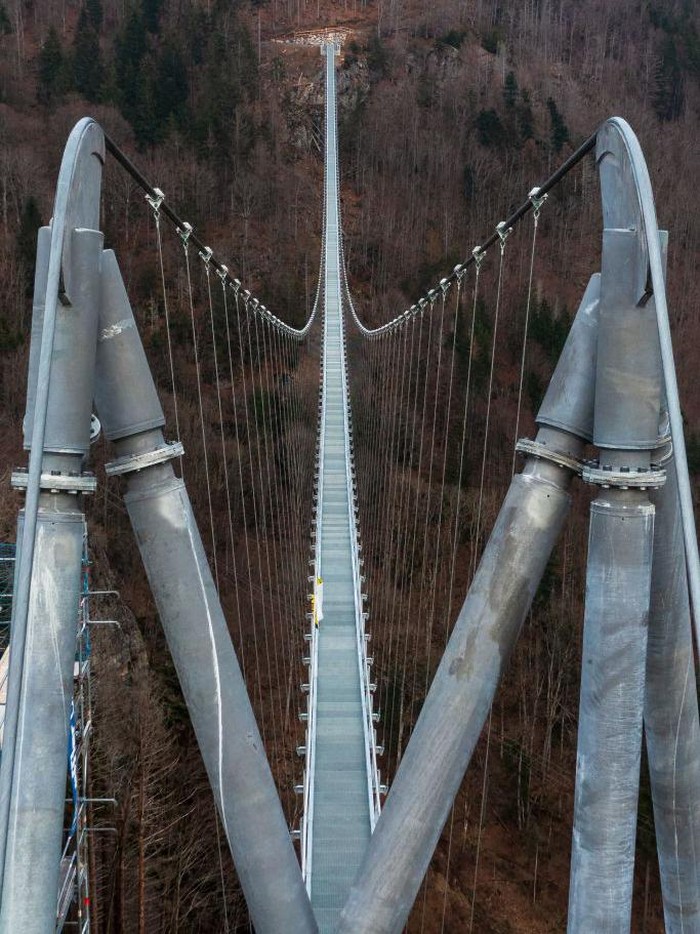 Jerman Bangun Jembatan Gantung untuk Wisata di Hutan Hitam TOPSHOT - A panorama of 27 pictures taken on March 3, 2023 shows a suspended footbridge under construction, overlooking a waterfall in Todtnau, southwestern Germany. - The construction of the 450 meters long bridge suspended at a height of up to 120 meters is expected to be completed in May 2023 and to become a major tourist attraction in the Black Forest. (Photo by PATRICK HERTZOG / AFP) (Photo by PATRICK HERTZOG/AFP via Getty Images)