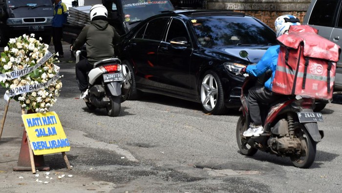 Warga Bogor Protes Jalan Rusak, Tandai dengan Karangan Bunga Sejumlah kendaraan melintas di jalan berlubang, Binamarga, Kota Bogor, Jawa Barat, Senin (6/3/2023). Warga meletakkan karangan bunga di lokasi jalan berlubang tersebut akibat banyaknya pengendara motor yang terjatuh sementara belum ada perbaikan dari dinas terkait di Pemerintah Kota Bogor. ANTARA FOTO/Arif Firmansyah/hp.